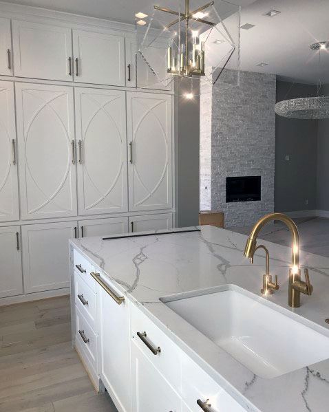 Modern kitchen with white cabinets, stacked stone backsplash, and marble countertops