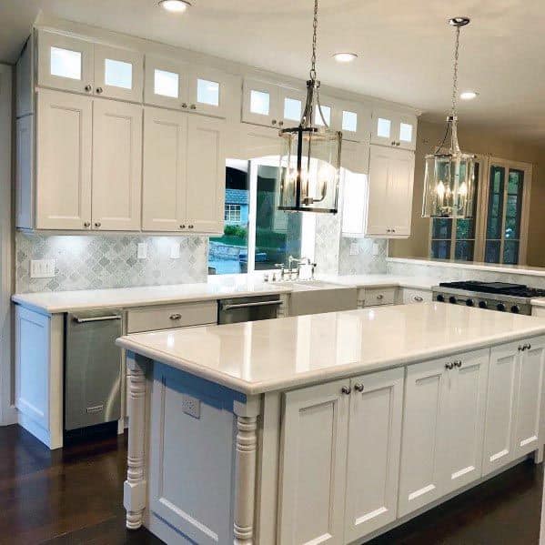 White kitchen with classic cabinetry, white countertops, and elegant pendant lights.
