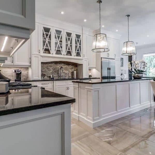 The kitchen has a white island, dark countertops, glass-front cabinets, and modern lighting