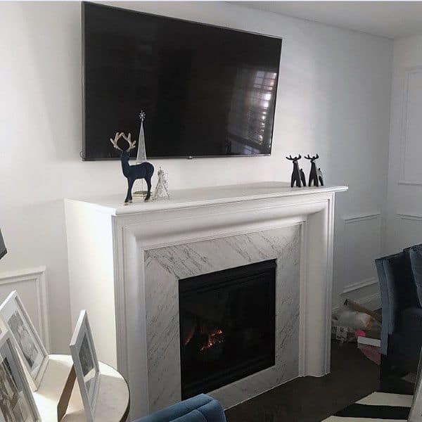 Traditional gas fireplace with a white marble surround, elegant mantel, and a TV mounted above.