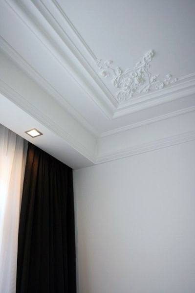 Elegant white ornate trey ceiling with intricate crown molding, complemented by modern lighting and dark curtains for a refined look
