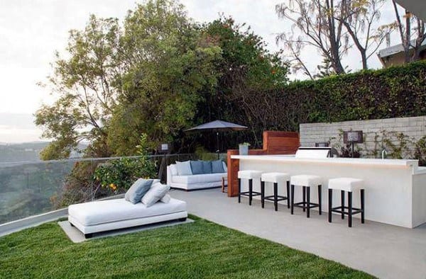 Chic rooftop backyard bar with white countertops, bar stools, and comfortable lounge seating.