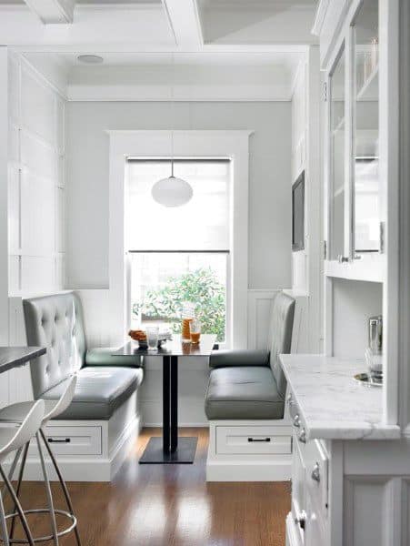 Cozy nook with bench seating by a window, featuring white and gray decor in the kitchen