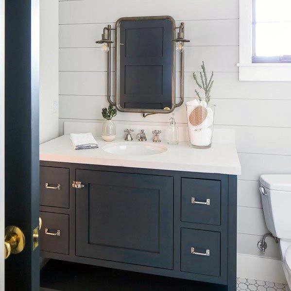 ornate mirror on white shiplap wall with gray cabinets