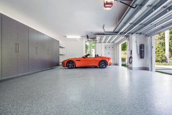 Bright garage with white ceiling, sleek storage cabinets, and an orange sports car.