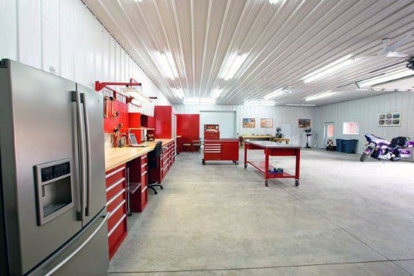 Spacious garage with white metal ceiling, red tool cabinets, and a functional workshop area.