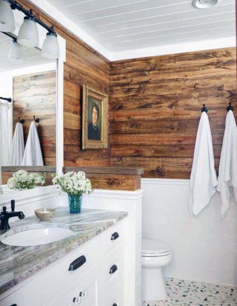 Rustic bathroom with wood accent wall, white vanity, granite countertop, and shiplap ceiling.