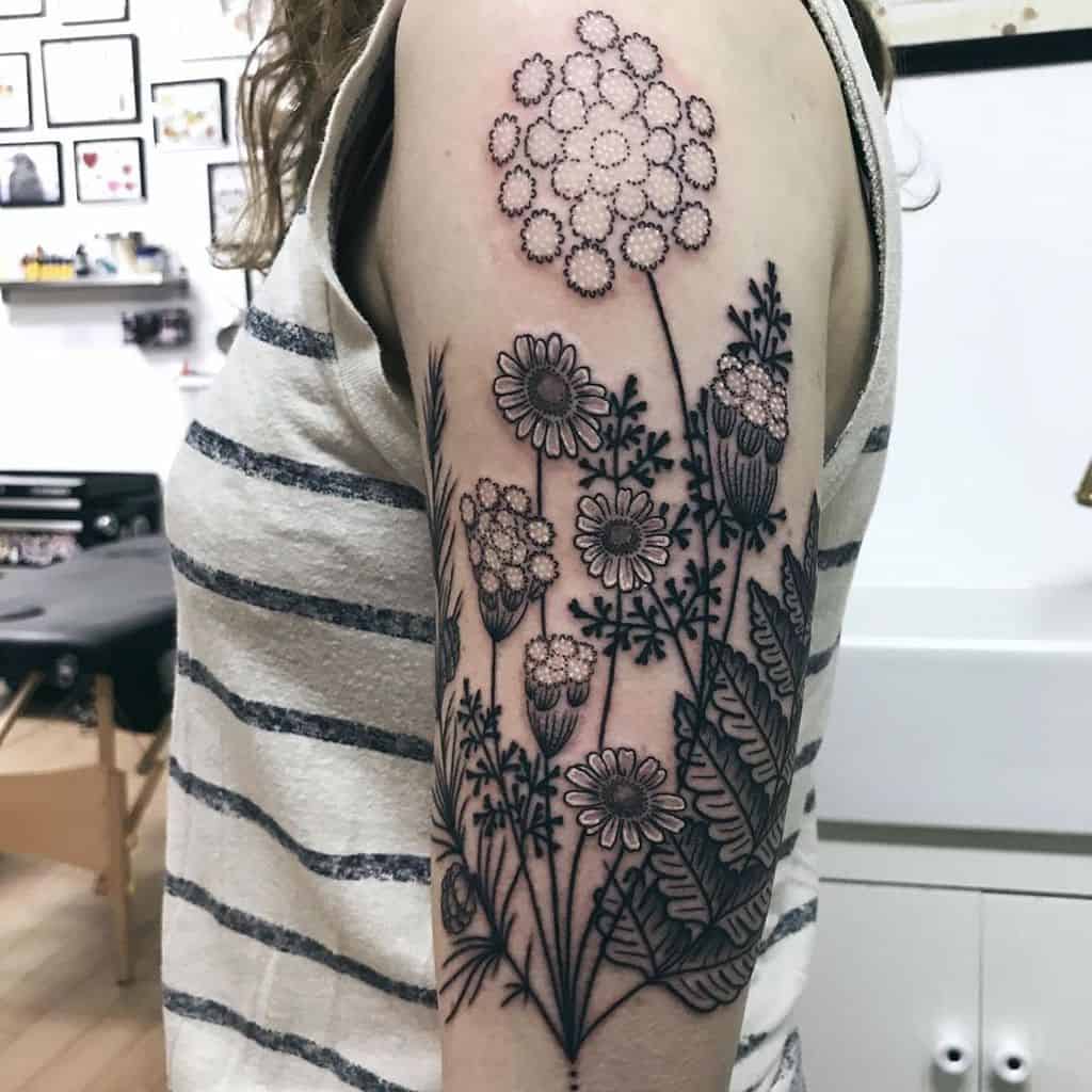 Upper arm tattoo large black and grey and white queen’s lace pine cone fern and daisy