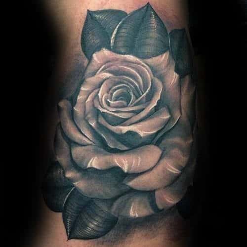 Tattoo of a detailed black and white rose with leaves