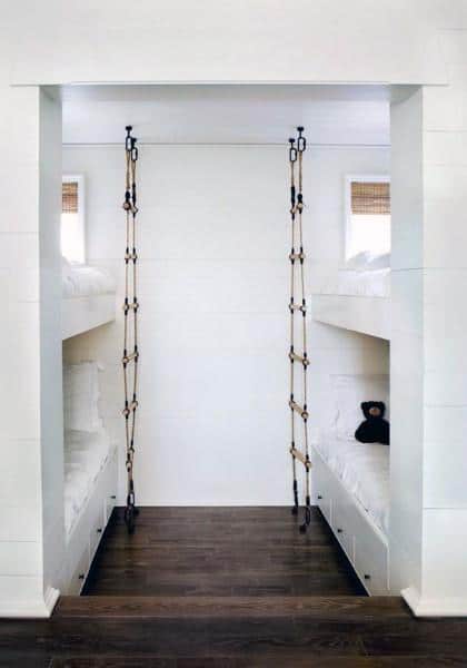 Bunk beds with rope ladders in a minimalist room, featuring a wooden bunk floor and minimal decor