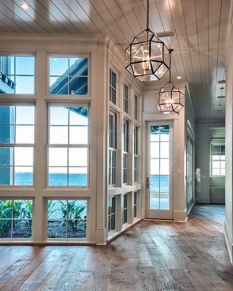 Bright hallway with white wood ceiling, large windows, glass pendant lights, and wood flooring.