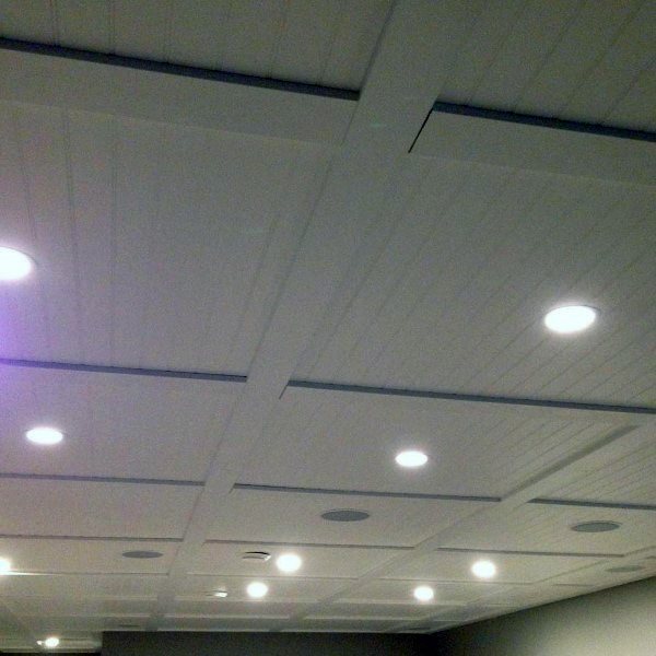 White shiplap ceiling with recessed lighting and built-in speakers for a modern basement design.