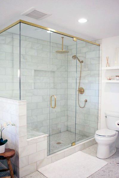 Modern bathroom with glass shower, gold fixtures, white tiles, and a tiled floor