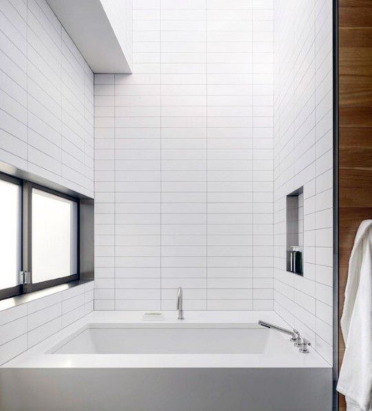 Modern bathtub with sleek white subway tile surround and built-in niche shelving.