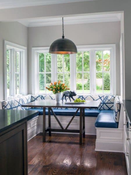 Cozy nook with blue cushioned seating, flowers, and a pendant light by large windows for breakfast moments