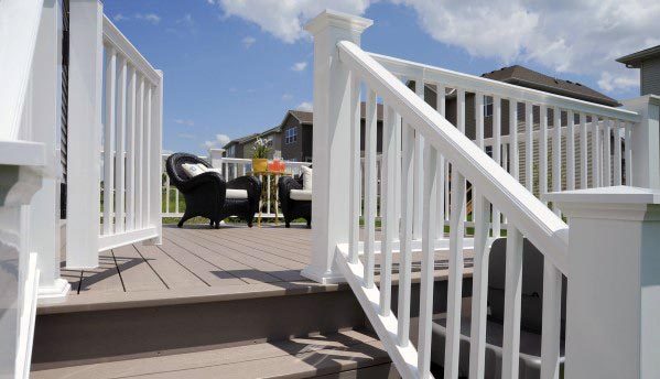 White-railed deck gate, black wicker chairs under a blue sky