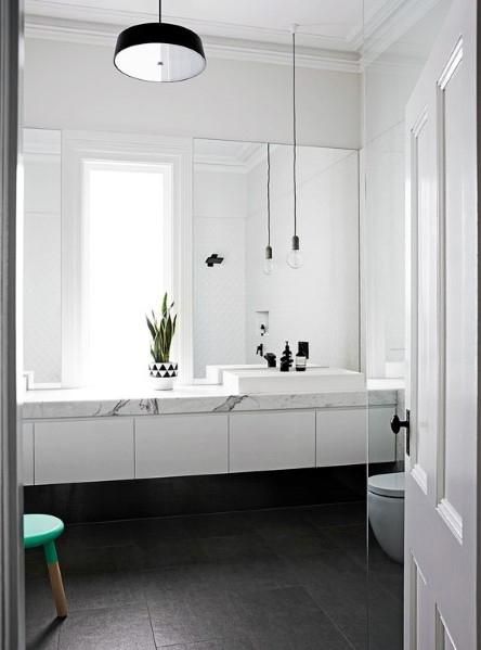Modern bathroom with a white vanity, marble countertop, hanging lights, and minimal decor.