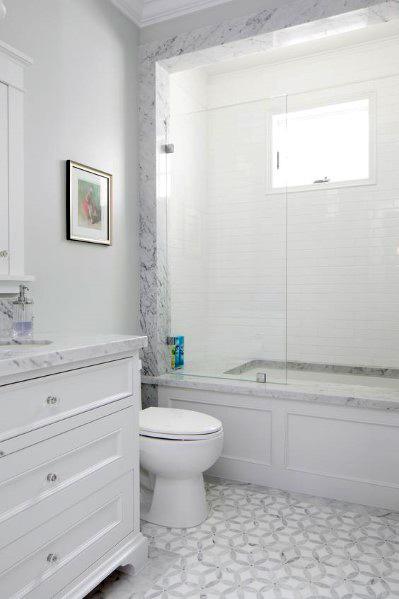 Elegant bathroom with white subway tile shower, marble surround, and patterned tile floor.