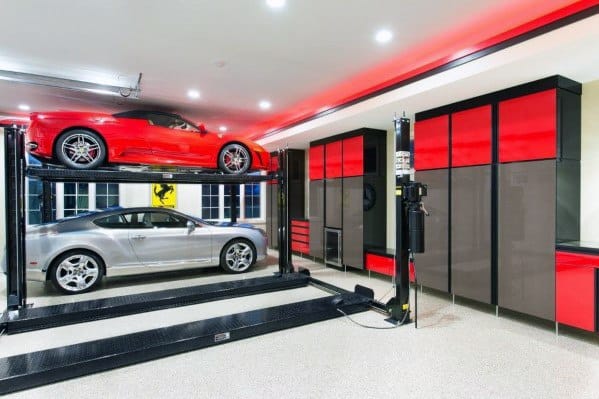 Modern garage with red LED accents, car lift, and sleek red and black storage cabinets.