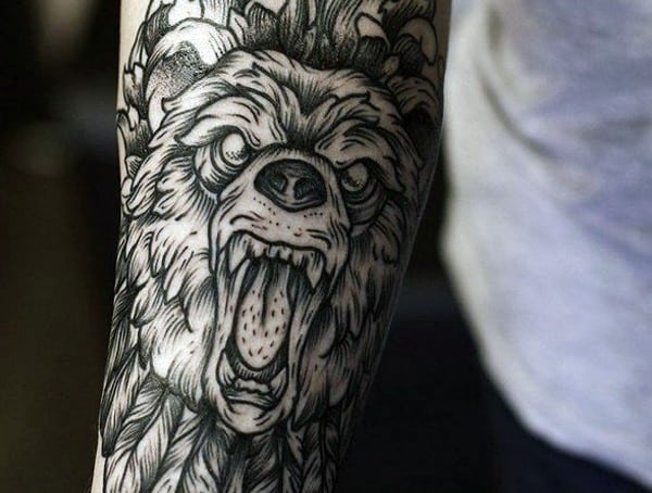 Tattoo of a roaring bear's head on a person's arm, with intricate black and grey detailing
