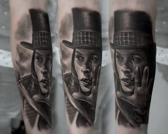 Black and grey Willy Wonka tattoo inspired by Johnny Depp’s version, showing a dramatic pose with gloved hand and intense gaze.