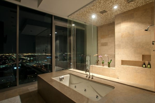 A modern bathroom with a city view, featuring a bathtub and a large glass shower