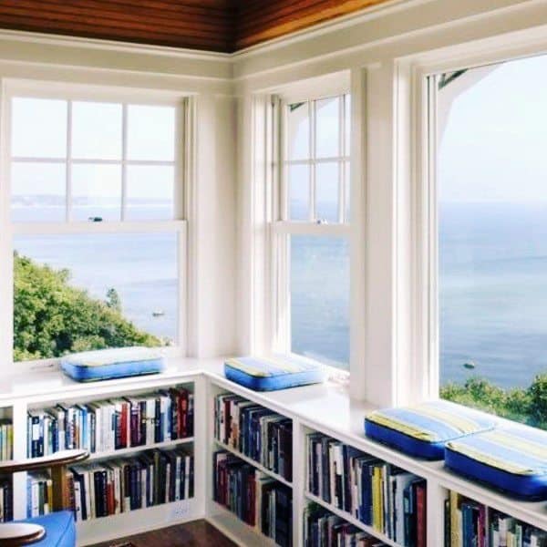 A cozy reading nook with ocean views, surrounded by bookshelves and cushioned window seats