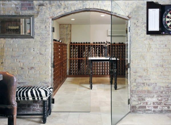 Glass door opening to a wine cellar with brick walls, wine racks filled with wine, a marble table, and a dartboard