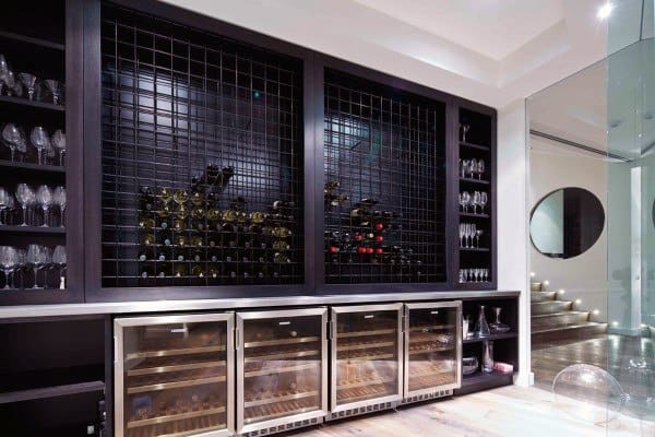 Modern wine cellar with glass racks, wine bottles behind metal grates, and coolers for pristine wine storage