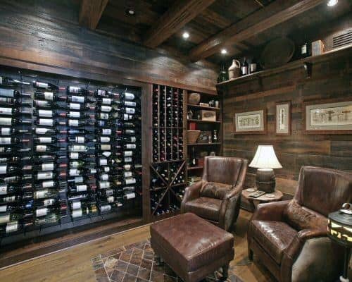 Cozy wine cellar with leather chairs, ottoman, and a wall-mounted wine rack in a wood-paneled room