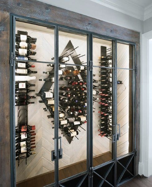 Glass-enclosed wine rack with various bottles displayed on angled shelves against a geometric marble backdrop
