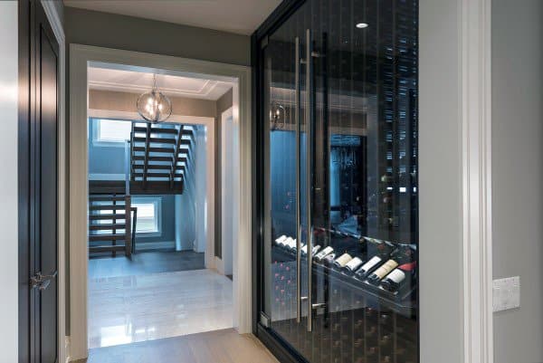 Modern hallway with a glass-enclosed wine cellar on the right and a staircase visible through a doorway