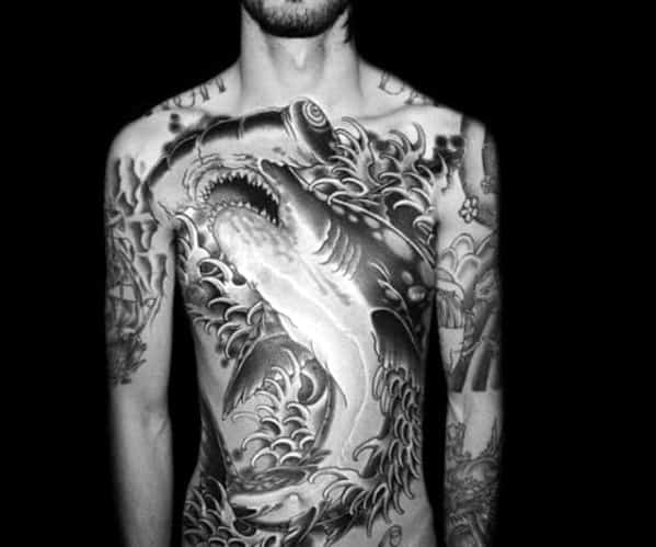Full chest tattoo of a shark and waves in black ink