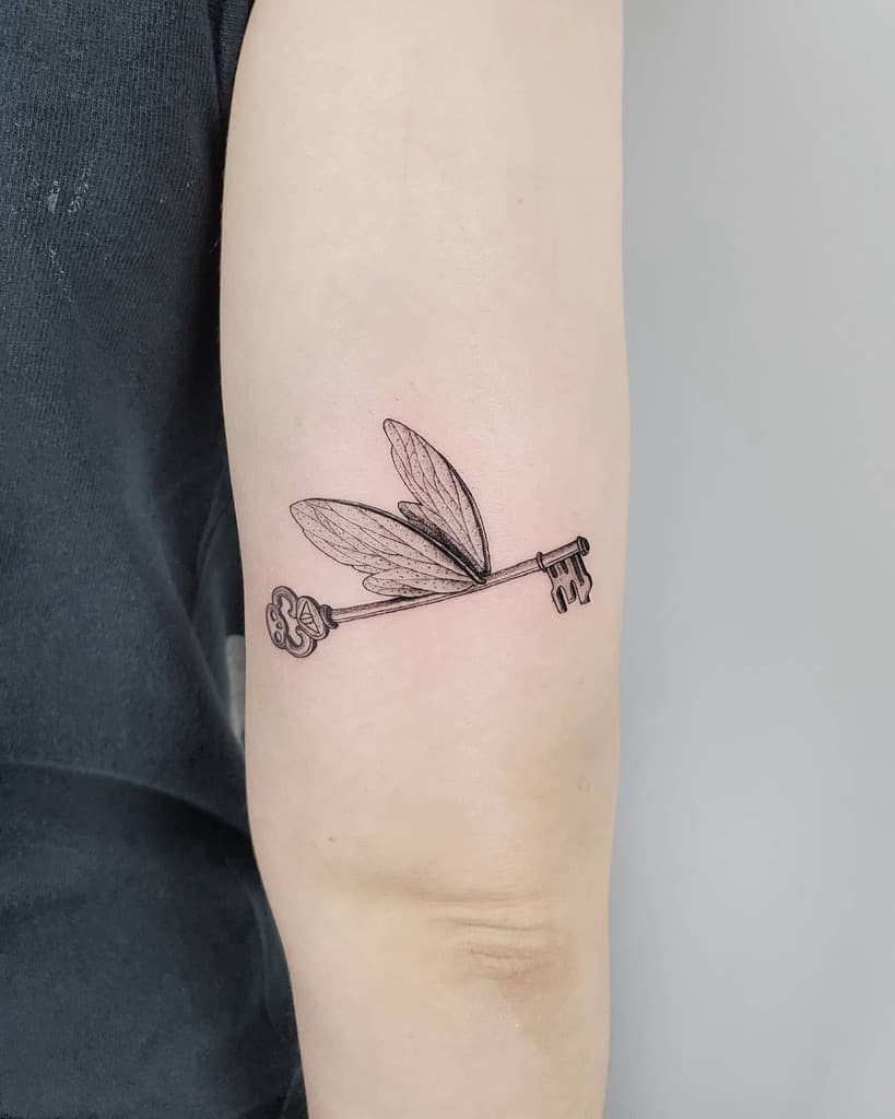 Flying key tattoo with delicate wings, inspired by the enchanted keys from Harry Potter, symbolizing mystery and adventure