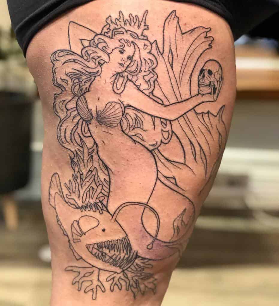 Linework tattoo of a mermaid holding a skull, surrounded by seaweed and an anglerfish with sharp teeth, blending fantasy and gothic elements.