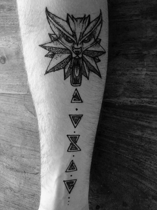 Minimalist Witcher forearm tattoo with the wolf medallion at the top and five magical sign symbols stacked vertically below it.