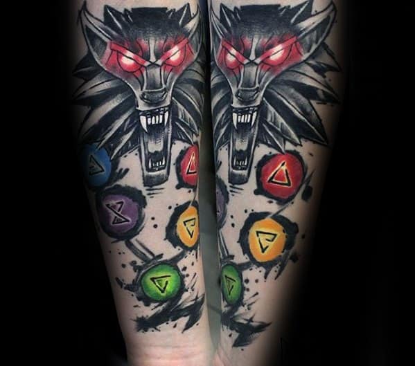 Vibrant Witcher forearm tattoo of the wolf medallion with glowing red eyes, surrounded by colorful magical sign symbols and black splatter.