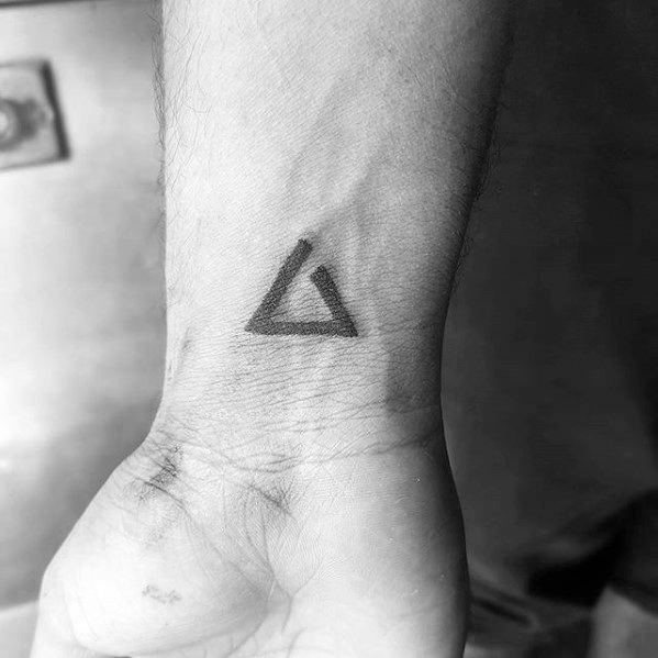 Simple Witcher wrist tattoo of the Aard sign symbol, done in bold black ink with a clean and minimalistic design.