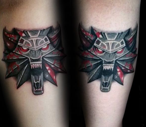 Fierce Witcher wolf medallion tattoo with glowing red eyes and blood-splattered accents, inked in bold black and red tones.
