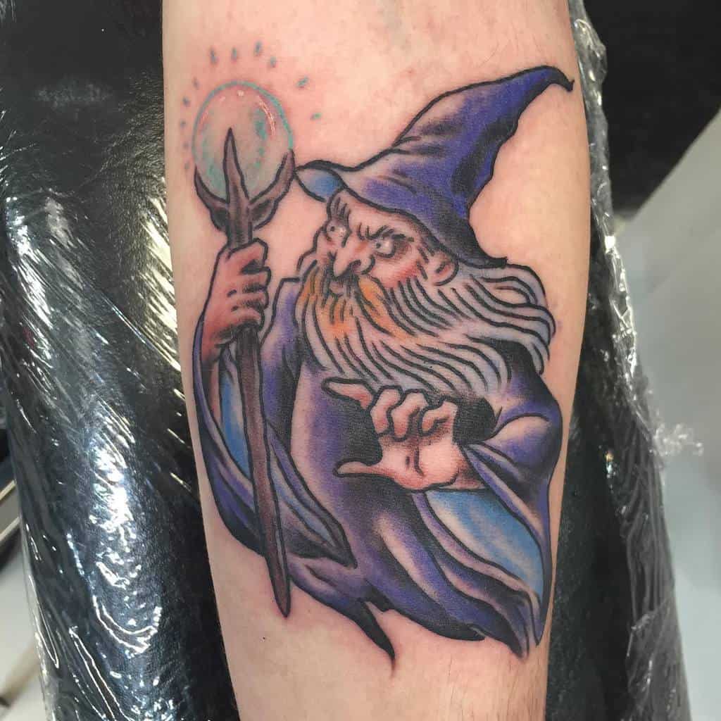 Classic Dungeons & Dragons tattoo of a wise wizard with a flowing beard, glowing staff, and mystical blue robes, casting a powerful spell