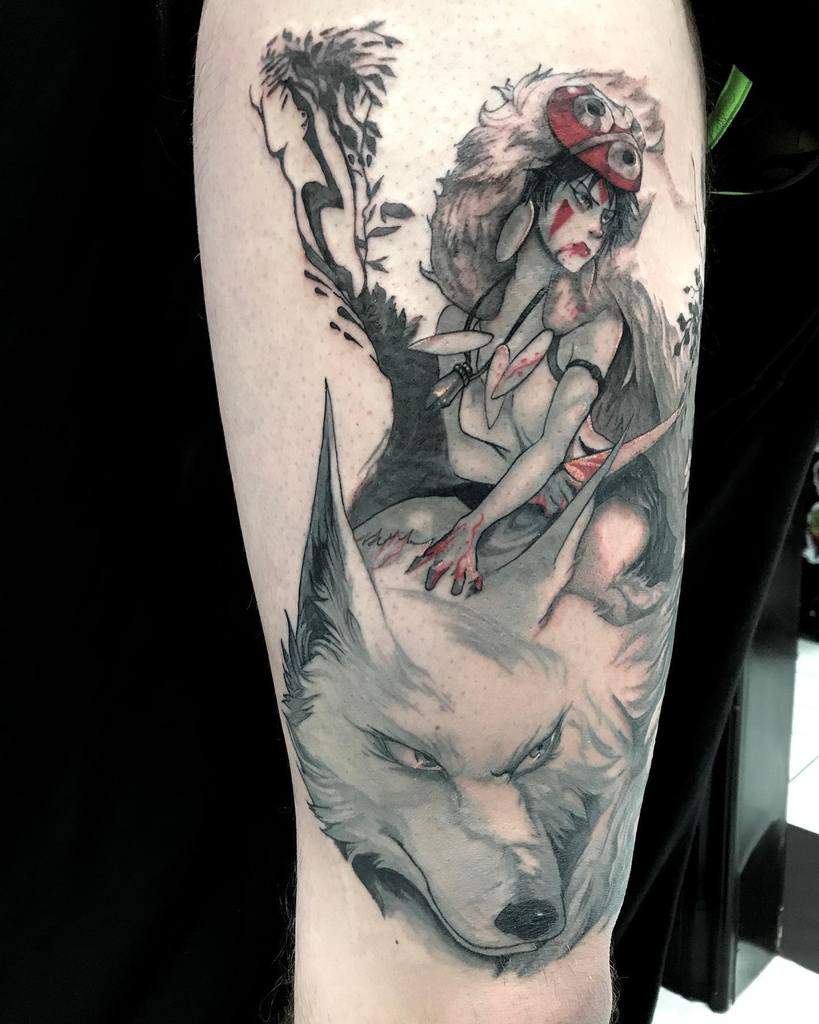 Black and grey tattoo of San crouching with her dagger, wearing her wolf pelt, with a fierce Moro below, accented with red ink details.