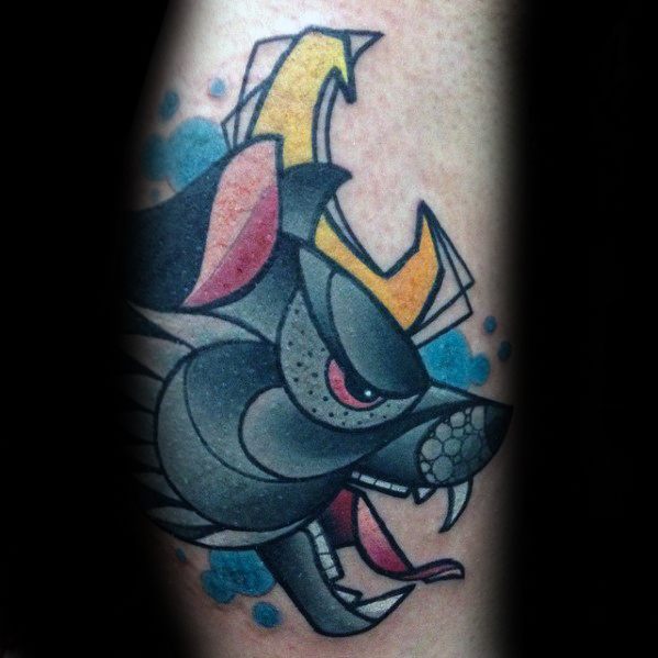 Cubist-style tattoo of a snarling wolf head with angular shapes, blue splatters, and bold yellow horns on the forearm.