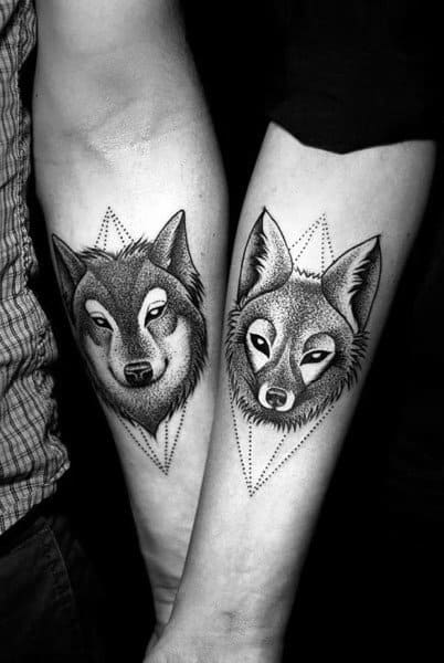 Matching forearm tattoos of a wolf and a fox inside dotted geometric triangles, symbolizing loyalty, intelligence, and a powerful yet balanced bond.