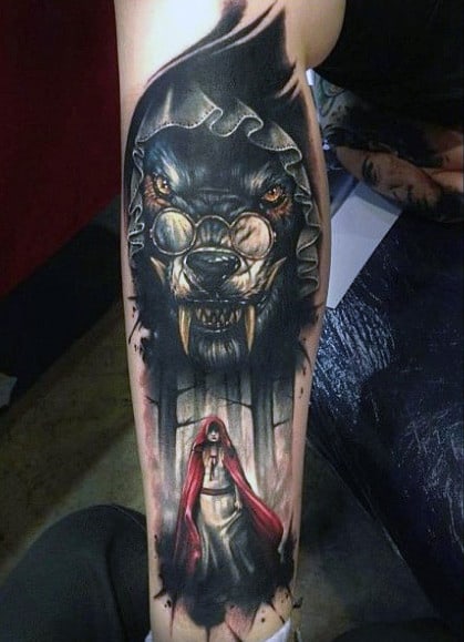 Tattoo of a fierce wolf and a cloaked figure on a person's arm