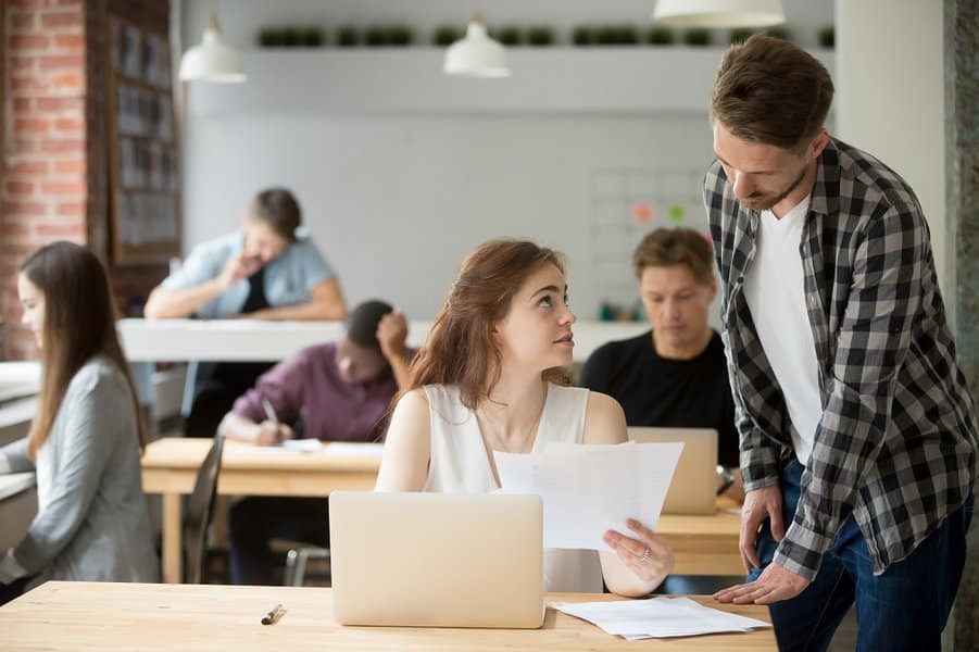 woman helping male colleague with documents