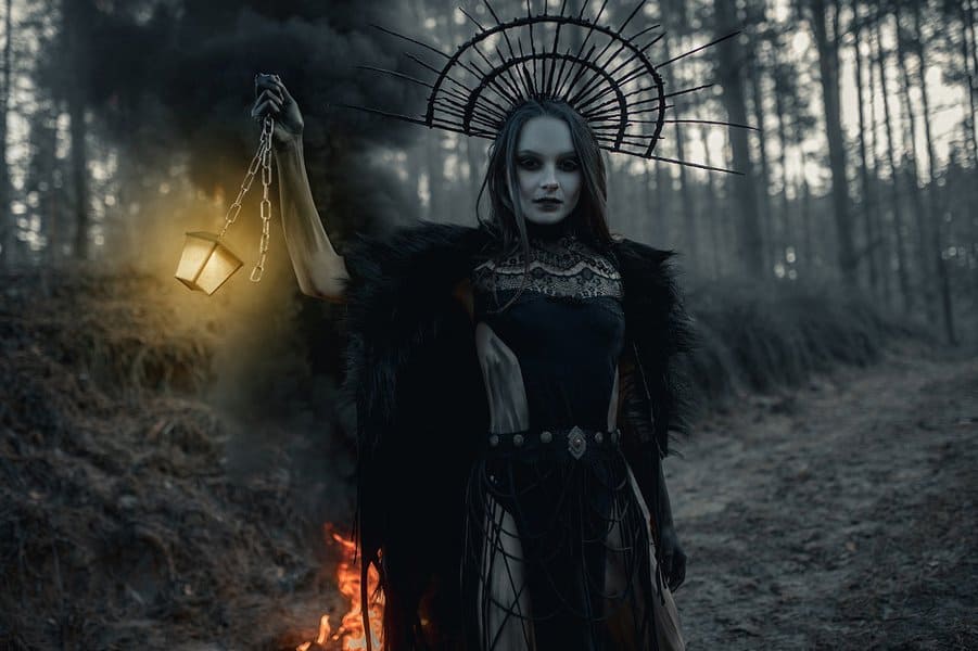 woman in image of witch stands in black dress