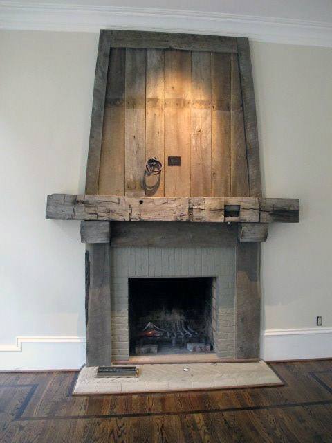Rustic fireplace with weathered wood mantel and surround, featuring a vintage industrial light.