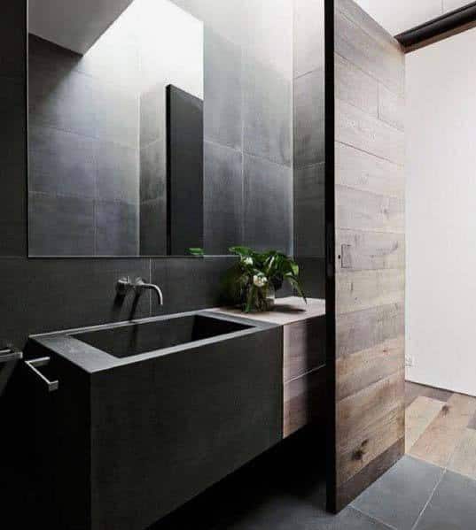 Modern black bathroom with stone sink, wood accents, and minimalist design.