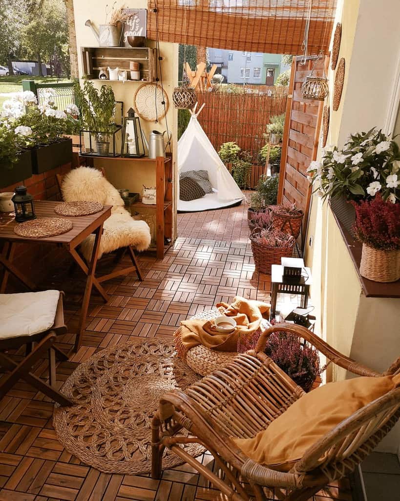 Cozy rustic patio with wooden furniture, wicker decor, plants, and a small outdoor tent.