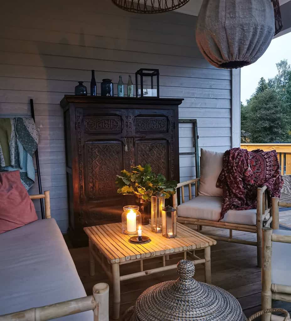 Inviting patio with bamboo furniture, soft lighting, and a vintage wooden cabinet for decor.